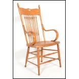 A 20th century American Windsor style country oak armchair raised on turned legs united by stretcher