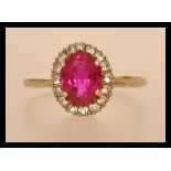 A hallmarked 9ct gold ring having a large central faceted synthetic ruby surrounded by a halo of