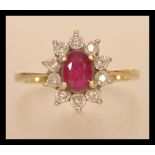 A hallmarked 9ct gold ruby and diamond cluster ring having a central faceted ruby with a halo of