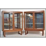 A pair of vintage retro 20th century teak wood glass bookcase display cabinets being raised on
