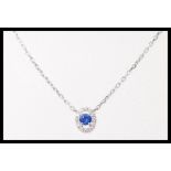 An 18ct white gold pendant set with a brilliant cut central sapphire with a halo of accent diamonds,