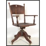 A Victorian 19th century oak Industrial office swivel desk chair - captains chair being raised on