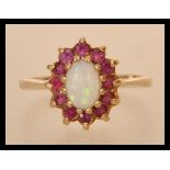 A hallmarked 9ct gold opal and ruby ring having a central opal cabochon with a halo of rubies.