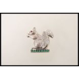 A silver brooch in the form of a squirrel set with a row of brilliant cut emeralds,having a red
