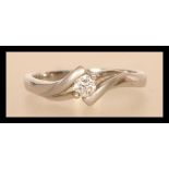 An 18ct white gold crossover diamond ring having a central diamond of approx 15pts. Weighs 3.7