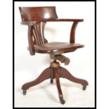 A 1930's oak office desk chair having a leather panel to the seat, pierced splat, bowed arms, four