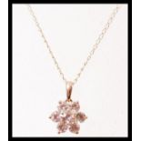 A 14ct gold flower head pendant set with five white sapphires on a gold chain, having a spring