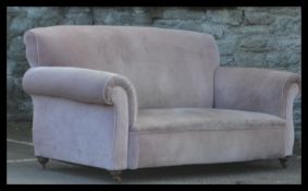 A large Victorian Chesterfield sofa being raised on bun feet having barrel arms and back rest