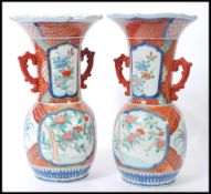 A pair of early 20th Century Japanese hand painted Imari vases, with bulbous bases and trumpet