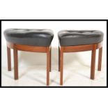 A pair of mid century triangular stools being raised on tapering turned legs with black faux leather