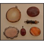 A selection of agate brooches and pendants to include a large stone pendant, a red stone pendant,