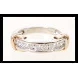A stamped 10k white gold ring having 8 channel set brilliant cut diamonds, and yellow gold