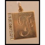 A yellow metal tests as 9ct gold necklace pendant having a monogrammed front with seven inset