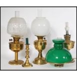 A collection of three brass oil lamps dating to the early 20th Century, each lamp raised on a