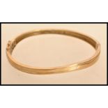 A yellow metal but tests as 9ct gold bangle bracelet having a hidden clasp AF with fold over