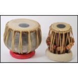 Two 20th century Indian table drums to include a polished metal cased drum and a wooden drum, both