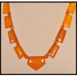 A vintage Art Deco amber bakelite necklace with yellow metal clasp. Large axe shaped panels with