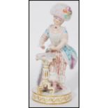 A late 19th century Meissen porcelain figure of a standing woman in 19th century costume by a tripod