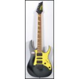 A vintage Ibanez Gio electric guitar having a black body with yellow scratch guard and black