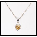 A stamped 14ct white gold pendant set with a heart shaped citrine and diamond accent stones, on a