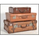 A stack of three vintage early 20th century graduating leather suit cases, each in brown leather