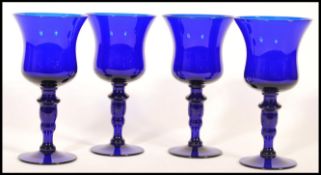 A set of four unsigned Bristol Blue glass wine goblets raised on a circular foot with knopped stem