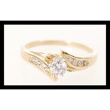 A ladies gold serpentine ring prong set with a brilliant cut diamond with further diamond accent