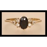 A hallmarked 9ct gold blue sapphire and white stone ring having a central faceted blue stone flanked