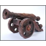 An early 20th century carved wooden large cannon raised on large wheels with geometric patterns