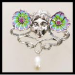 A silver Art Nouveau style plique a jour brooch in the form of a face and two flowers having a pearl
