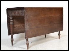 A 19th century country oak drop leaf / gate leg dining table being raised on turned legs with