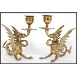 A pair of late 19th century cast brass candlesticks modelled as dragons with wings raised scrolled