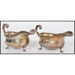 A pair of early 20th century silver hallmarked sauce gravy boats raised on hood feet with acanthus