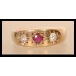 A hallmarked 9ct gold three stone ring having a central faceted red stone in star setting flanked by