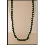 A Chinese deep green jade bead necklace consisting of over 60 circular jade beads.