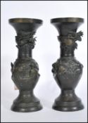 A pair of 20th century Chinese bronze vases raised on domed circular bases with Greek key borders to