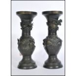 A pair of 20th century Chinese bronze vases raised on domed circular bases with Greek key borders to