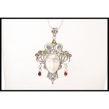 A silver necklace having a pendant in the form of a face having decorative scrollwork set with