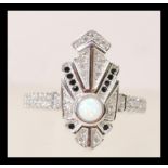 A silver and cz art deco style ring set with a central round opal and black accent stones. Size P.5.