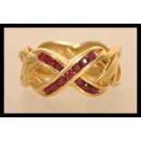A hallmarked 18ct gold band ring set with round cut rubies in a kiss motif . Marked ©FM88. Import