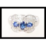A stamped 750 white gold art deco style diamond and sapphire ring set with three central oval cut