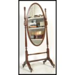 An early 20th Century Edwardian mahogany floor standing cheval mirror of oval form flanked by turned