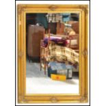 A large antique style contemporary gilt wall mirror with decorative frame having inset bevelled edge