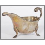 An early 20th century silver hallmarked sauce gravy boat raised on hood feet with acanthus leaf