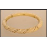 An early 20th century ivory and gold banded bangle. The carved bangle having twist design with