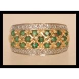 A 14ct gold diamond and emerald ring having three rows of emeralds flanked by two rows of illusion