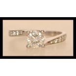 A 14ct white gold and diamond ring having a central brilliant cut diamond of approx 65pts and