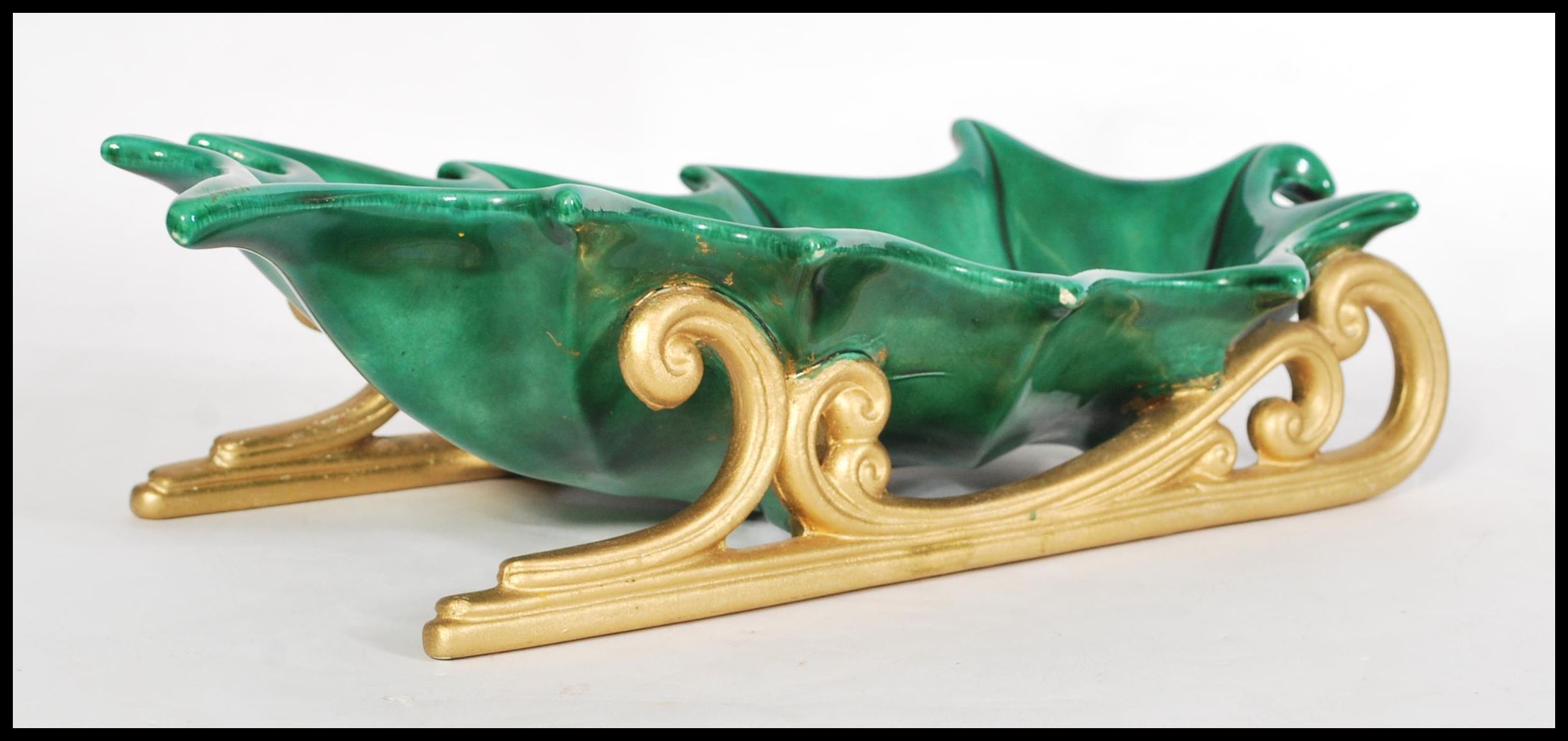A vintage 20th century ceramic Christmas decoration in the form of a large holly leaf raised on gilt