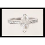 A stamped 750 white gold ring set with a marquise cut diamond and channel set brilliant cut diamonds