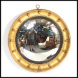 An early 20th Century giltwood convex wall mirror in reeded ebonised slip and concave moulded